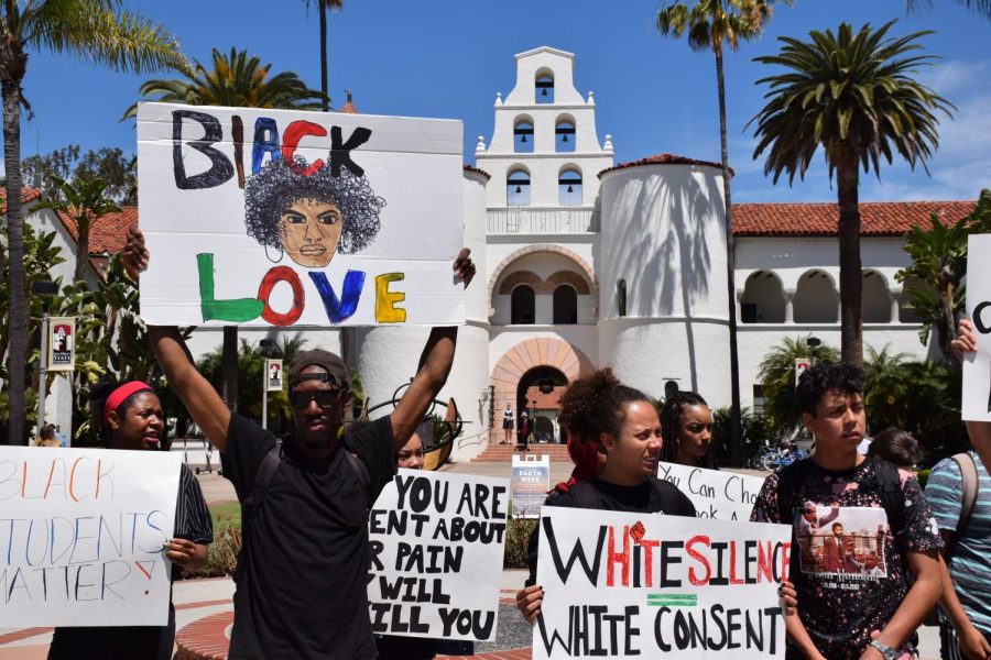 Student activists hold signs in front of Hepner Hall at San Diego State during the rally on Thursday, April 18, 2019.