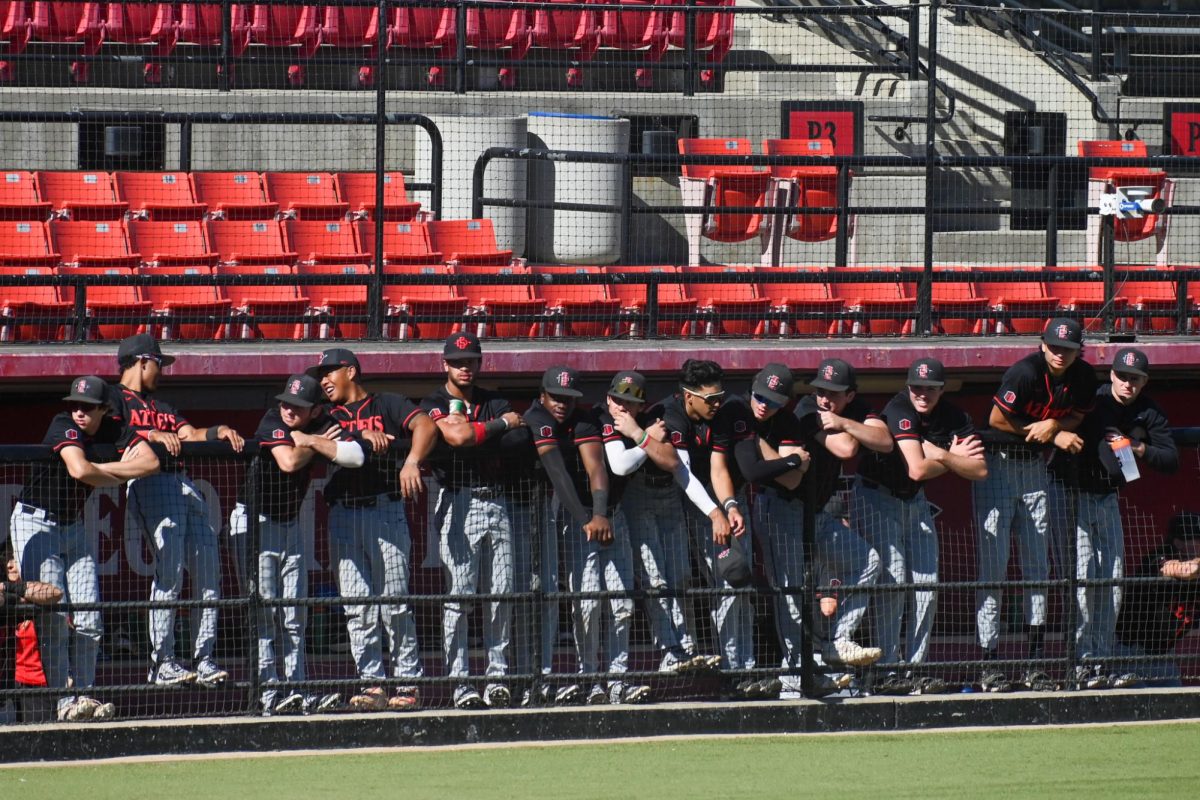The San Diego State Baseball team stands and watches the game from the dugout at Tony Gwynn Stadium. 